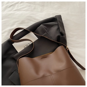 Close-up of caramel brown leather bucket bag with golden buckle and sleek stitching