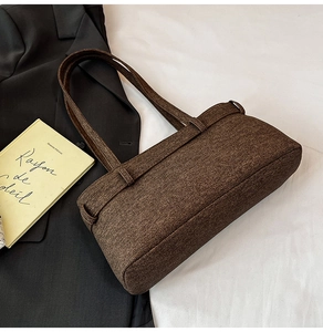 Detailed texture of brown vintage canvas underarm bag with double straps over a suit