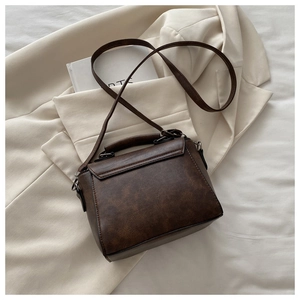 Detailed view of brown vintage crossbody bag with flap and bronze-toned hardware