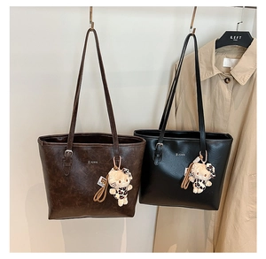 Detail of large brown and black tote bags with cute character charms on a coat rack