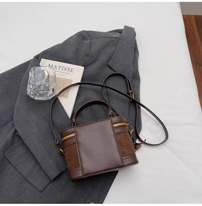 Detail of a brown leather vanity bag featuring mixed textures on a minimalist background