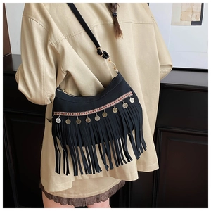 Detail of ethnic black shoulder bag featuring red woven trim and golden tassel charms