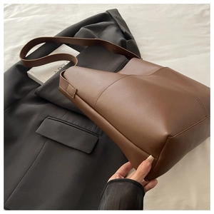 Detail of coffee brown tote bag with vertical stitching and wide shoulder strap texture