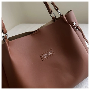 Close-up of brown faux leather tote bag showing fine texture and Foshian brand leather tag