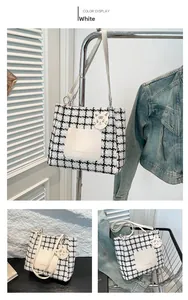 Detail of black and white houndstooth tote bag with leather pocket and cat charm