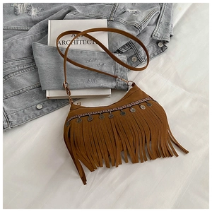 Detail of caramel brown suede crossbody bag with ethnic woven trim and long fringe tassels