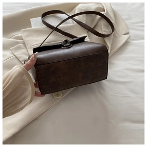 Detail of dark brown vintage leather square bag with metallic twist-lock closure