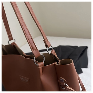 Close-up of silver metal rings connecting leather straps on a brown tote bag