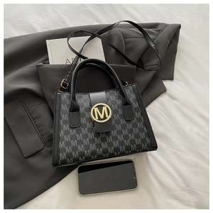 Vista dall'alto di borsa tote nera monogramma con dettagli dorati e accessori professionali