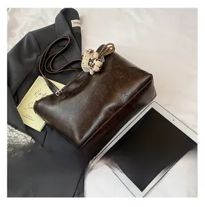 Flat lay of retro brown leather tote with a plush leopard charm and commute essentials