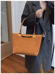 Close-up of caramel suede tote bag with leather handles shown on a model's shoulder