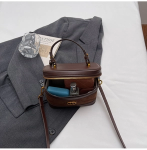 Detail of dark brown square vanity bag with dual zippers and gold hardware detail