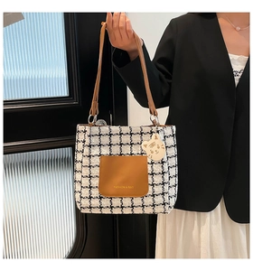 Detail of houndstooth tote bag with brown leather pocket and cute tiger charm