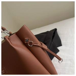 Detail of silver ring handle and brown leather texture on a large tote bag