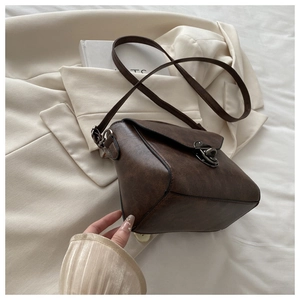 Detail of vintage dark brown faux leather shoulder bag with a metal twist lock closure