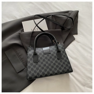 Dettaglio dell'elegante borsa tote nera con motivo a M goffrato su pelle testurizzata