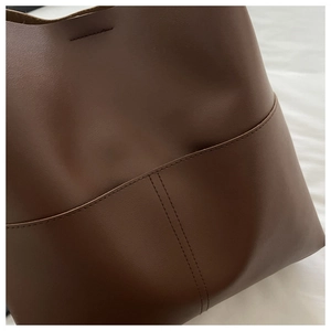 Detailed close-up of brown leather bucket bag showing premium stitching and texture