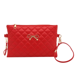 Red quilted crossbody bag with gold bow decoration and sleek minimalist square design