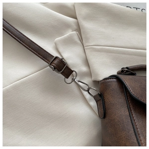Close-up of adjustable strap and bronze hardware on retro brown square bag