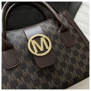 Dettaglio borsa marrone con fibbia dorata M e trama monogramma di lusso
