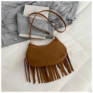 Close-up of brown suede saddle bag with fringe details and adjustable shoulder strap
