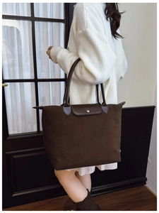 Detail of dark brown matte tote bag with chocolate leather handle and snap button closure