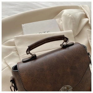 Detail of vintage dark brown faux leather bag with crackle texture and metal buckle