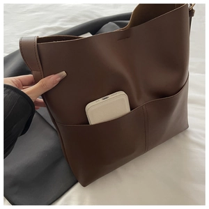 Detail view of brown tote bag featuring two front open pockets and large storage space