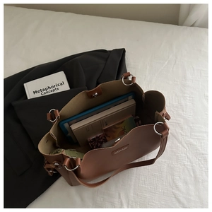 Detail view of large brown PU leather tote bag with metallic ring and brand tag