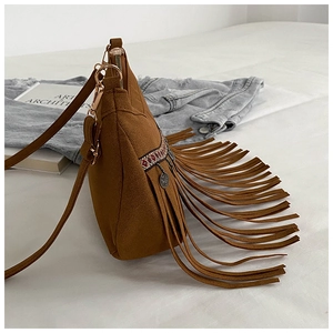 Detailed side view of brown suede shoulder bag featuring long fringe and ethnic embroidery
