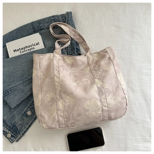 Detailed close-up of large canvas tote bag with white floral prints and front pocket