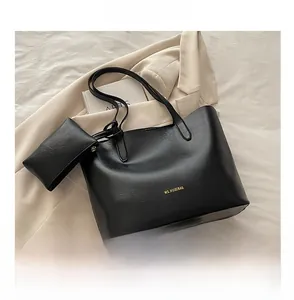 Detail of black faux leather tote with inner pouch, gold logo, and large storage space