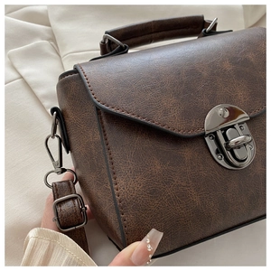 Close-up of vintage brown leather handbag with metallic buckle and textured finish