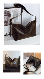 Detailed close-up of dark faux leather texture and golden zipper hardware on shoulder bag