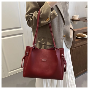 Detail view of burgundy leather tote bag with stylish metallic rings and thin straps