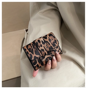 Close-up of leopard print tri-fold wallet held by hand with elegant nail art