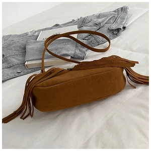 Detail of brown suede shoulder bag featuring long side tassels on a white background