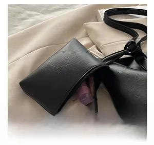 Macro shot of black pebbled leather mini tote bag showing spacious interior with makeup items