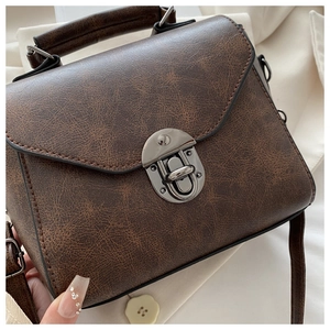 Close-up of retro brown handbag with vintage cracked leather texture and silver clasp