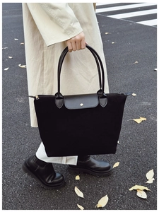 Detail of black tote bag with leather flap and golden metal buckle for casual commuting