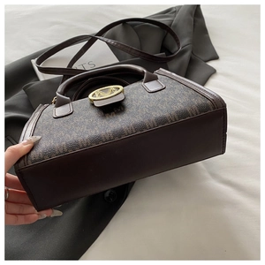 Dettaglio borsa in pelle marrone monogrammata con fibbia M dorata e tracolla regolabile