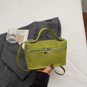 Chic green suede square bag with heart zippers and a crossbody strap in a modern setting