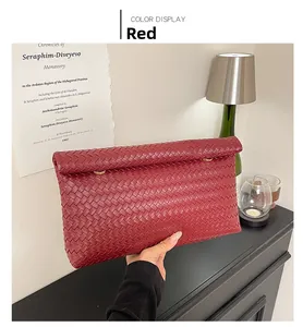 Dettaglio della pochette intrecciata rossa con anelli d'oro e texture premium
