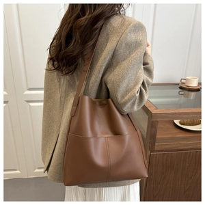 Brown leather bucket bag with decorative stitching shown in a lifestyle model setting