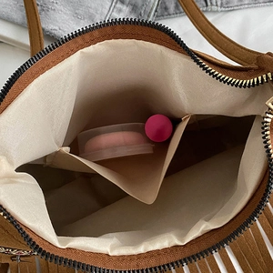 Interior view of brown suede handbag with zipper closure and ivory fabric lining
