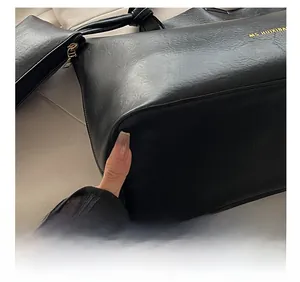 Detailed close-up of high-quality stitching and litchi texture on a black tote bag