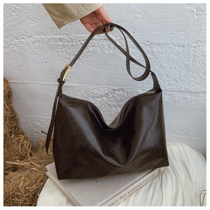 Detail of dark brown vintage shoulder bag with soft leather texture and gold hardware details