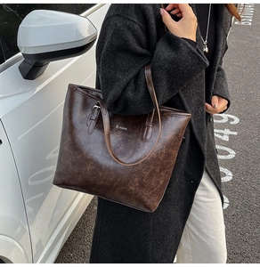 Detail of a dark brown large tote bag with vintage marble texture and logo on the side