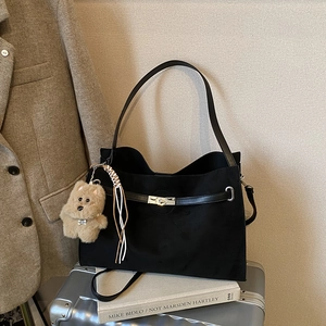 Retro black matte tote bag with silver twist lock and plush puppy charm on a suitcase