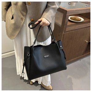 Detail of a minimalist black matte leather tote bag with stylish decorative patch